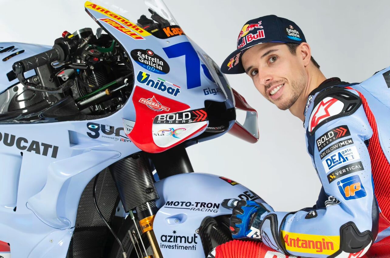 Gresini Racing rider beside a MotoGP motorcycle featuring MOTO-TRON Racing branding